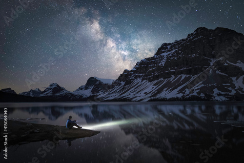 A man on the shore of Bow Lake in the Canadian Rockies viewing the Milky Way during an early Summer night.