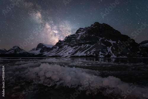 Ice blocks washed ashore Bow Lake with the Milky Way shining over the Canadian Rockies in the early Summer.