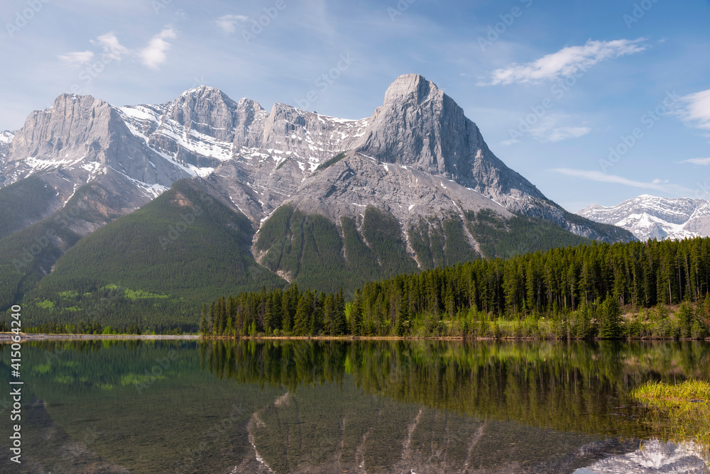 Mount Lawrence Grassi and Ha Ling Peak reflect in a gentle and calm Rundle Forebay on a late Spring morning.