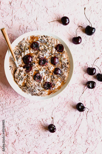 Overnight oats topped with halved cherries and spoon in white bowl