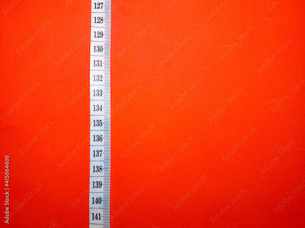 Selective focus.Measuring tape on a red background.Shot were noise and film grain. Selective focus.Measuring tape on a red background.Shot were noise and film grain.
