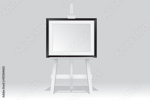 Wooden easel stand with picture frame on white background