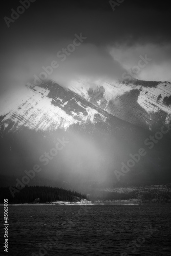 A snow squall is illuminated by of shaft of sunlight over Abraham Lake in the Canadian Rockies.
