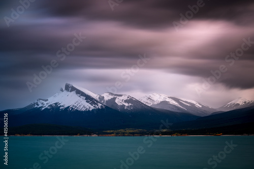 A long exposure of stormy skies over Abraham Lake and the Canadian Rockies with Kista Peak on the left.