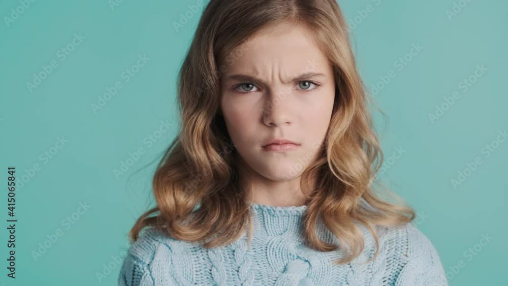 Serious blond teenager girl looking angry waving no on camera over blue background. Disagree expression Serious blond teenager girl looking angry waving no on camera over blue background. Disagree expression