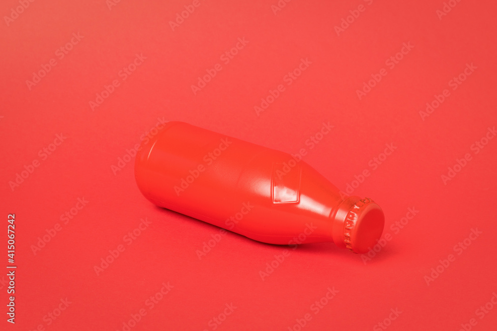 A red glass bottle lying on a red background. A red glass bottle lying on a red background.