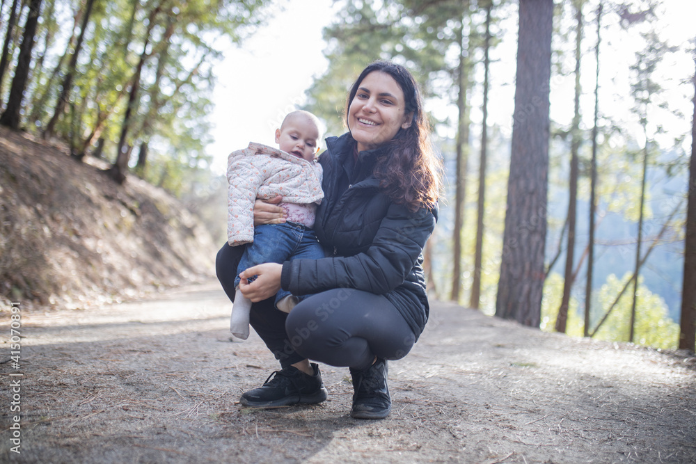 Happy woman holding her adorable baby in the forest Happy woman holding her adorable baby in the forest