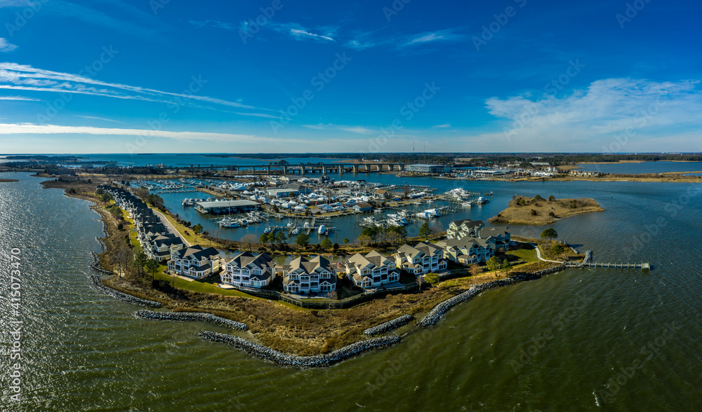 Aerial sunny winter view of luxury duplex residential neighborhood on a manmade promontory with luxury sail boats docked in the marina at Kent Island Narrows Maryland USA