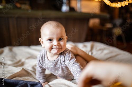 Adorable and happy baby lying on stomach above a bed