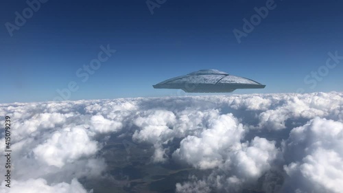 Ufo Flying Saucer hovering over Clouds,
Metalic shape from plane point of view, Alien invasion concept
