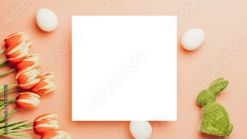 Easter background. Golden, white colour egg in basket with spring tulips, feathers on pastel pink background in Happy Easter decoration. Spring holiday top view concept.