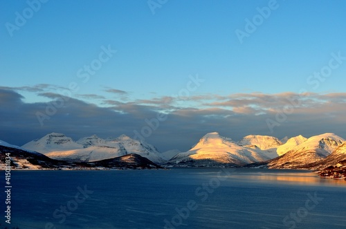 sunset over fjord and snowy mountain range in northern Norway