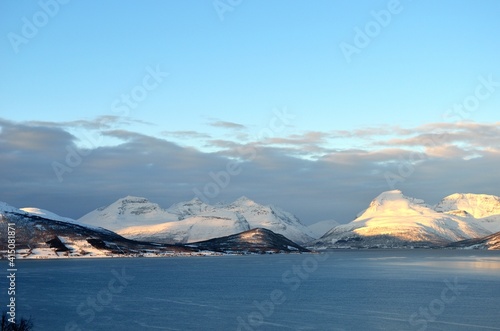 sunset over fjord and snowy mountain range in northern Norway