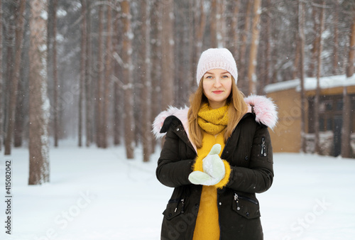Attractive young Caucasian blonde in winter outdoors in a snowy forest. The concept of recreation and living in the winter outside the city. Space for text