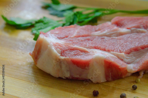 Fresh raw pork steak, isolated on a wooden background. Large piece of fillet of meat close-up