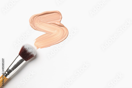 Sample of makeup foundation and brush on white background photo