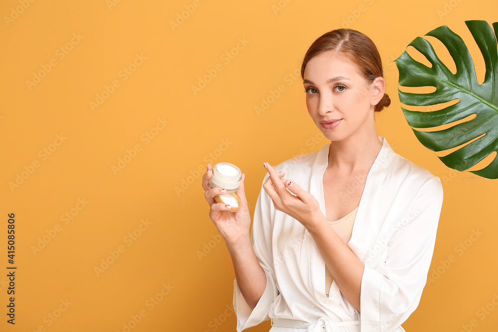 Beautiful young woman with facial cream and tropical leaf on color background Beautiful young woman with facial cream and tropical leaf on color background