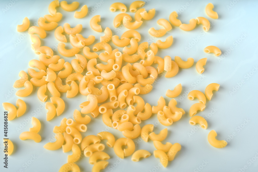 uncooked elbow macaroni on a white background.
uncooked elbow macaroni on a white background.