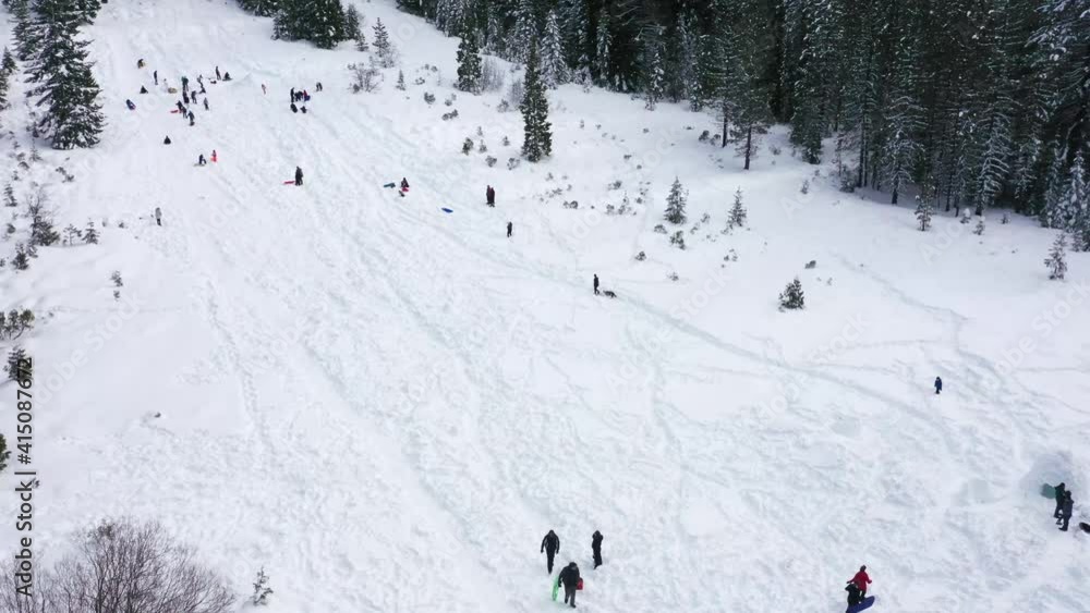 People walking and sledding down a hill in the winter. People walking and sledding down a hill in the winter.