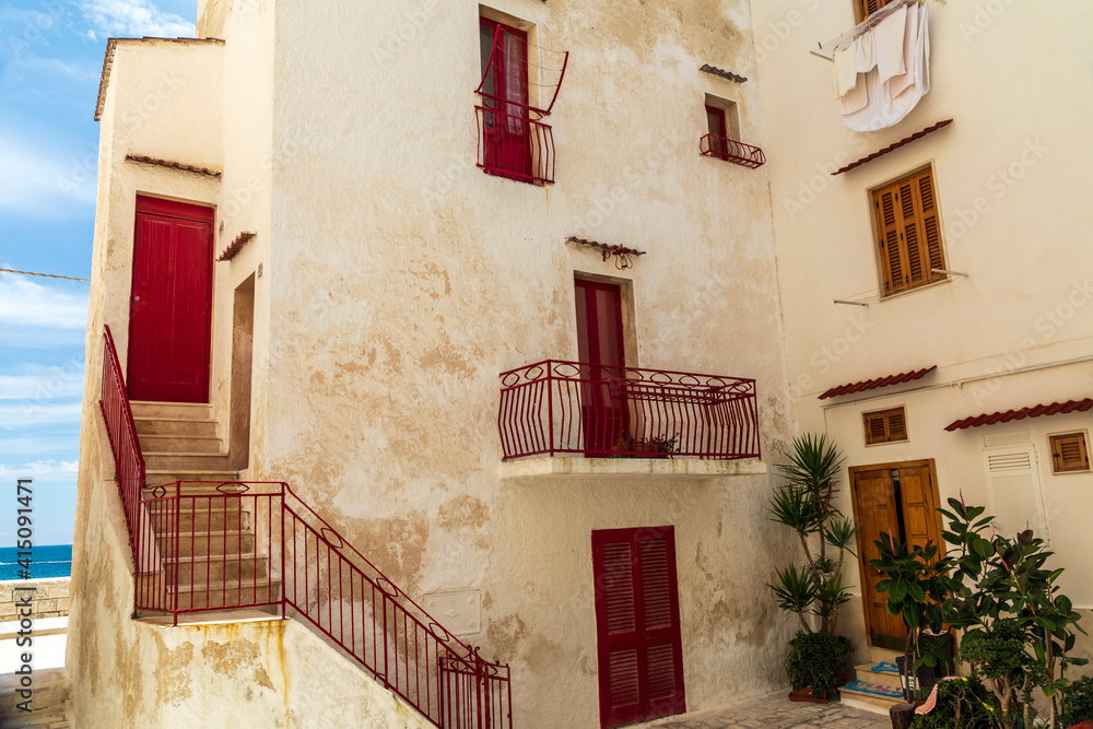 Italy, Apulia, Metropolitan City of Bari, Monopoli. Red doors and railings on a stucco building.