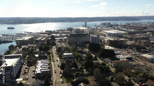 Cinematic drone panning footage of Bremerton, Manette, Sinclair Inlet, Puget Sound Naval Shipyard, the downtown marina, ferry terminal and shops in the background in Kitsap County, Washington State photo