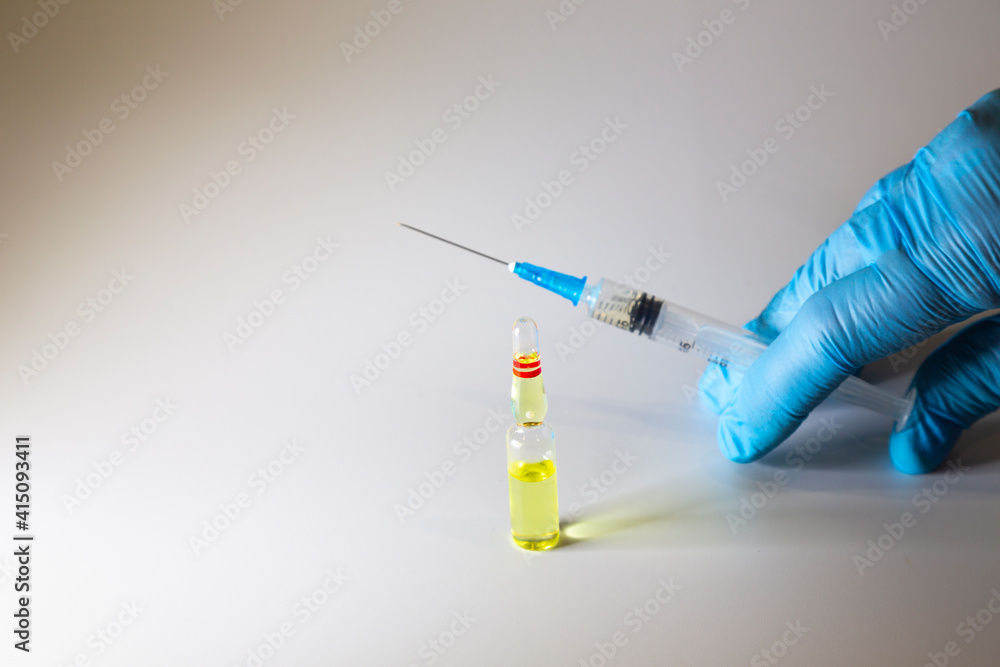 syringe with medicine in the hand of a doctor in a blue glove and a bottle of medicine, syringe with medicine in the hand of a doctor in a blue glove and a bottle of medicine,