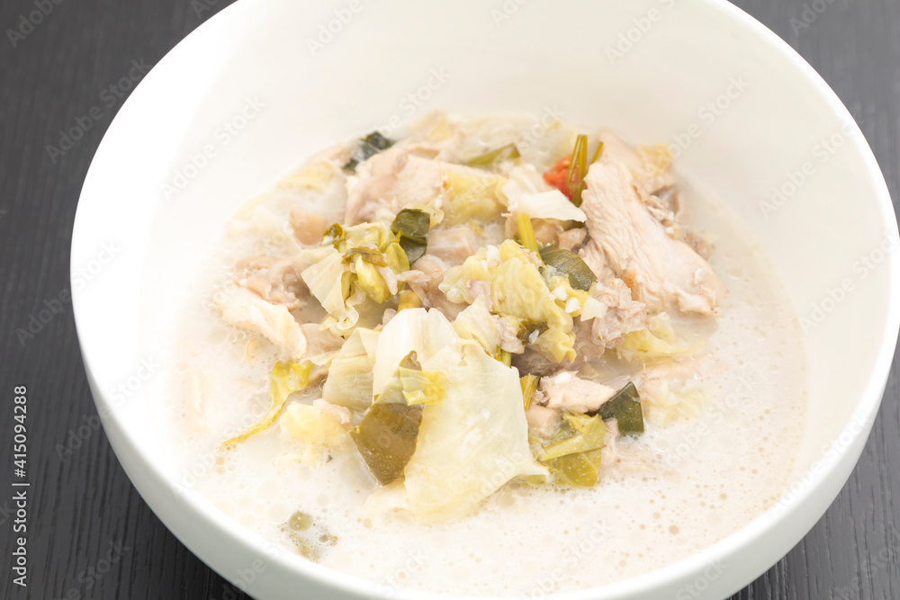 Tom Kha Gai or Thai Coconut Chicken Soup in white bowl isolated on black backdrop.