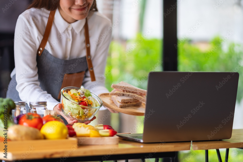 A woman videoblogger cooking and filming salad and sandwich in the kitchen, online learning cooking class concept A woman videoblogger cooking and filming salad and sandwich in the kitchen, online learning cooking class concept