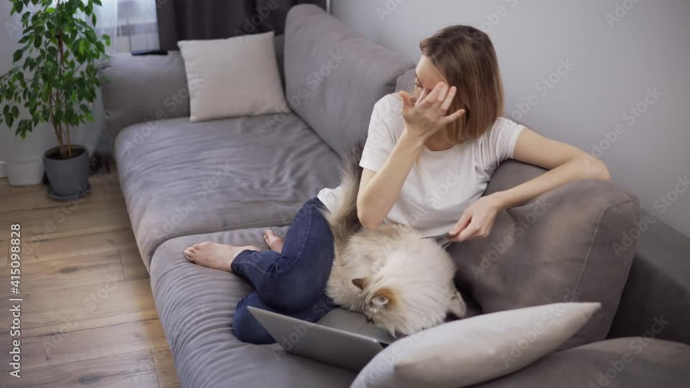 Blonde woman sitting on a sofa, pays for purchases online with a credit card and laptop Blonde woman sitting on a sofa, pays for purchases online with a credit card and laptop