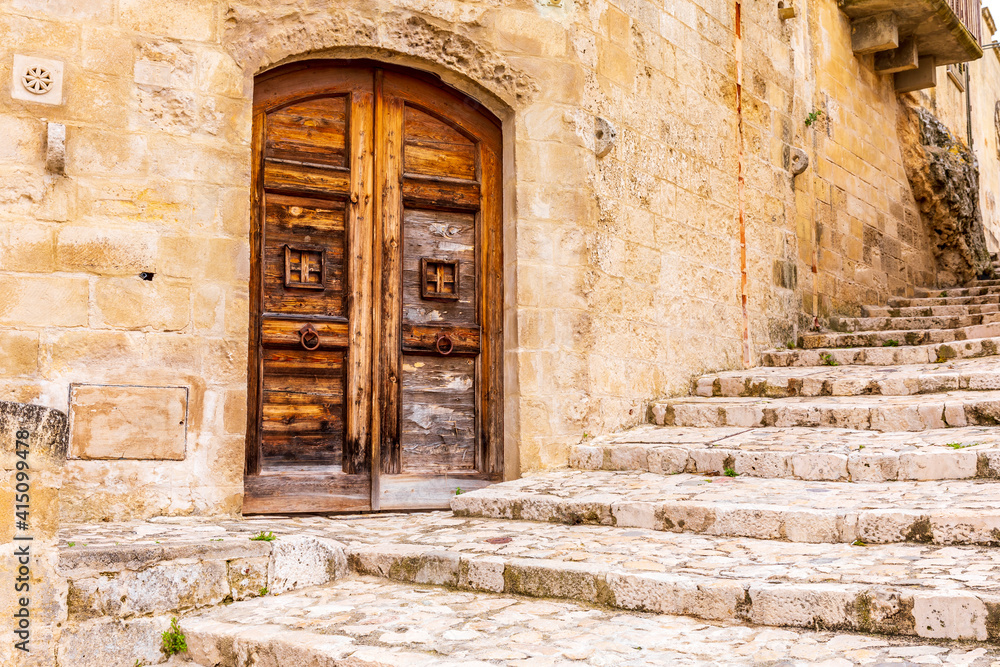 Italy, Basilicata, Province of Matera, Matera. Old wooden door in a stone wall above stone steps. Italy, Basilicata, Province of Matera, Matera. Old wooden door in a stone wall above stone steps.