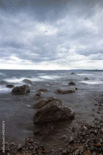 piedras en orilla de playa con agua sedosa en día nublado
