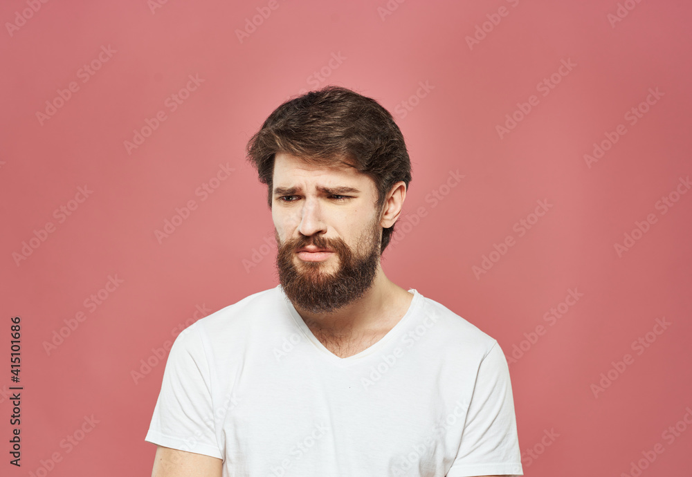 A man in a white T-shirt with a beard on a pink background Copy Space