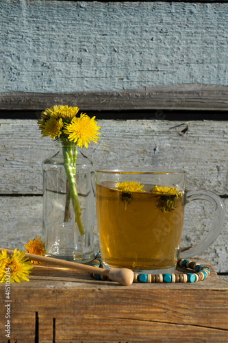 Medicinal Tea from dandelion in  glass cup with honey dandelion against a blue rustic wooden wall  with copy space photo