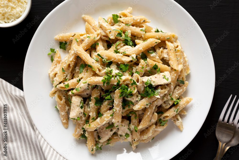 Homemade Chicken Alfredo Penne with Parsley on a black background, top view. Flat lay, overhead, from above.
