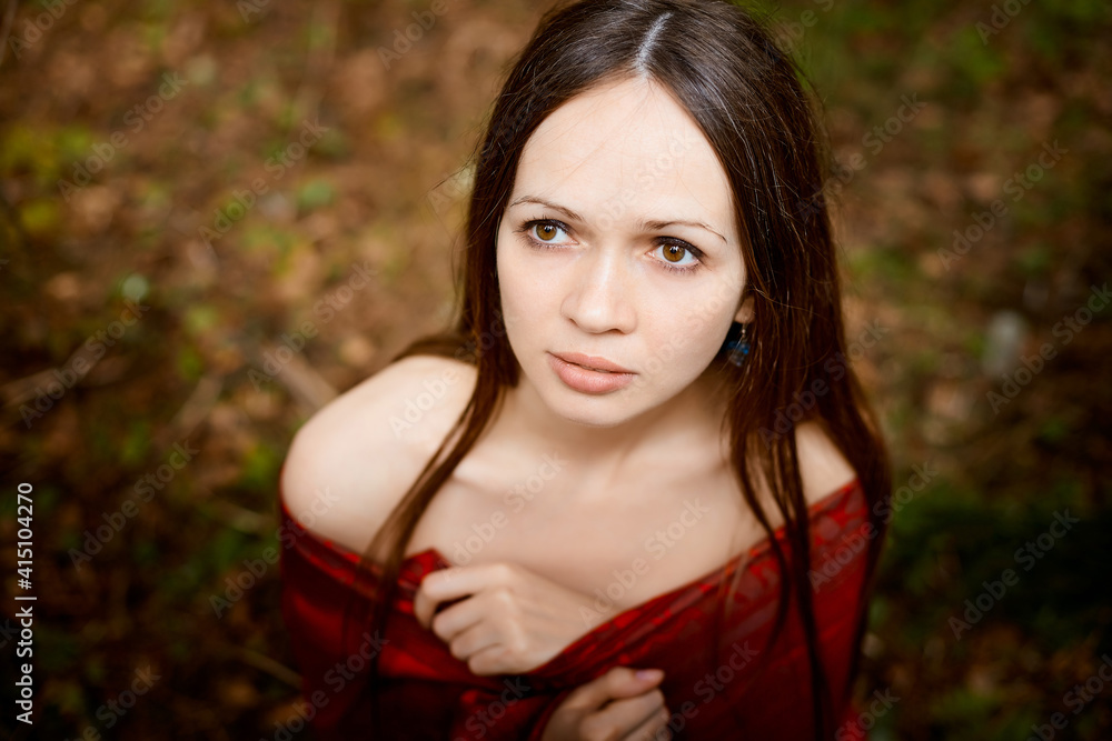 Fototapeta premium Beautiful young brunette woman with long hair in a forest pines and firs on a summer day