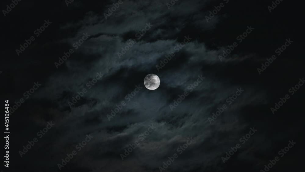 Dark clouds passing in front of a bright full moon during the night Dark clouds passing in front of a bright full moon during the night