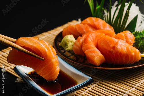 Sashimi, Salmon, Japanese food chopsticks and wasabi on the wood table.