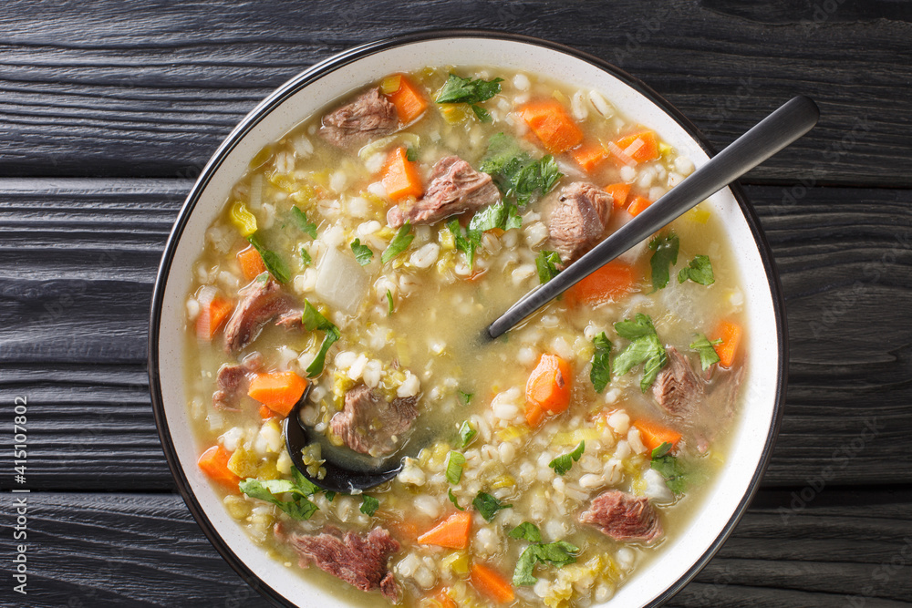 Tasty Scotch Rich broth filled with bite-sized pieces of root vegetable and tender lamb closeup in the plate on the table. Horizontal top view from above Tasty Scotch Rich broth filled with bite-sized pieces of root vegetable and tender lamb closeup in the plate on the table. Horizontal top view from above