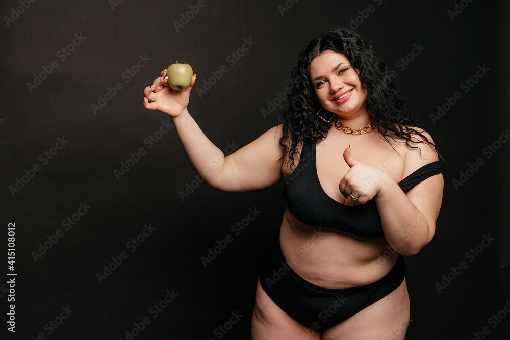 Plus size model in lingerie, fat sexy woman in underwear on black studio  background, body positive concept, full length portrait,a beautiful plus  size model holds an apple in her hand foto de