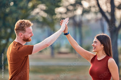 Two young sporty man and woman exercising in urban park.