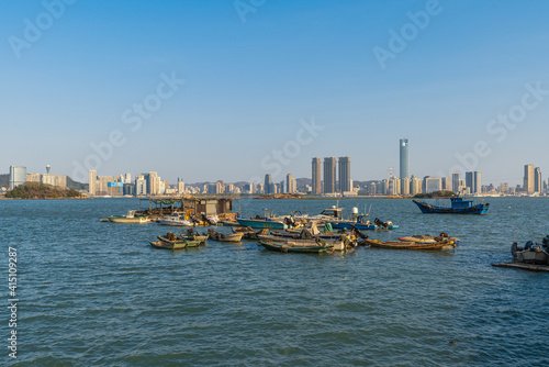 Xiamen Haicang Bay Park landscapes, Fishing Boats on the ocean and Xiamen City Skyline at distance