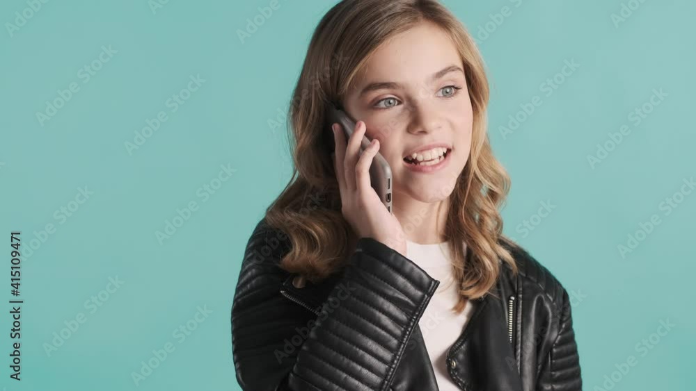 Pretty stylish blond teenage girl discussing news with friend talking on phone over blue background. Distant communication Pretty stylish blond teenage girl discussing news with friend talking on phone over blue background. Distant communication