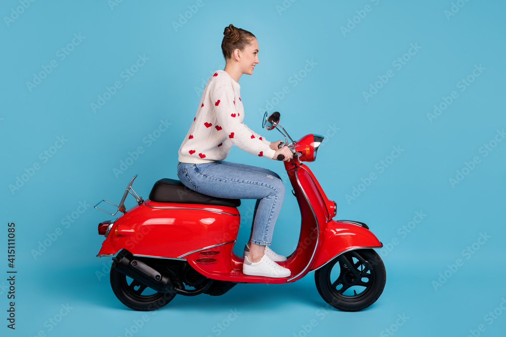 Profile photo of young girl ride moped wear heart print pullover jeans footwear isolated blue color background Profile photo of young girl ride moped wear heart print pullover jeans footwear isolated blue color background