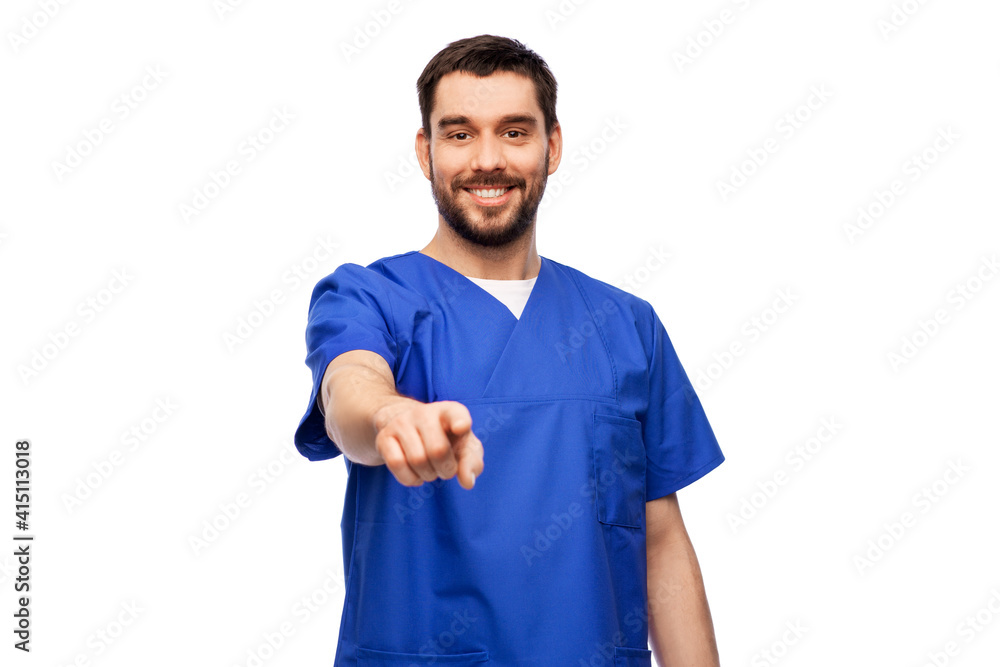 healthcare, profession and medicine concept - happy smiling doctor or male nurse in blue uniform pointing finger to camera over white background healthcare, profession and medicine concept - happy smiling doctor or male nurse in blue uniform pointing finger to camera over white background