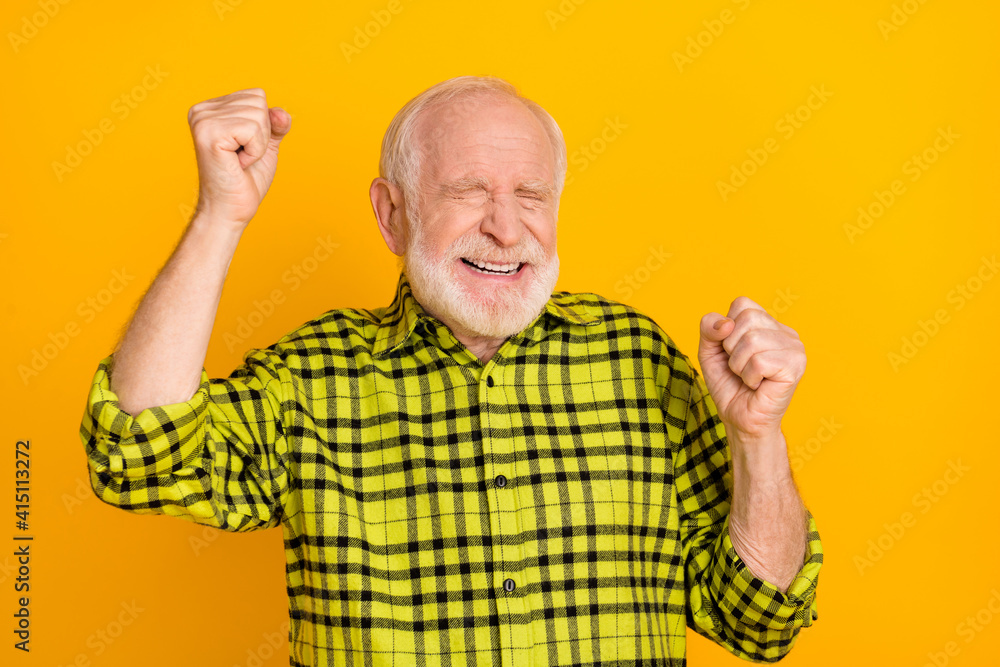 Photo of crazy aged man happy positive smile celebrate win victory ecstatic lottery fists hands isolated over yellow color background Photo of crazy aged man happy positive smile celebrate win victory ecstatic lottery fists hands isolated over yellow color background