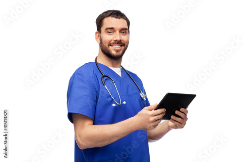 medicine, healthcare and technology concept - happy smiling doctor or male nurse in blue uniform with stethoscope using tablet pc computer over white background