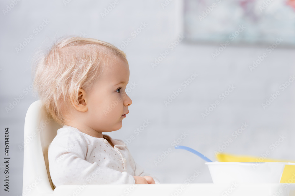 side view of little boy sitting on baby chair near bowl side view of little boy sitting on baby chair near bowl