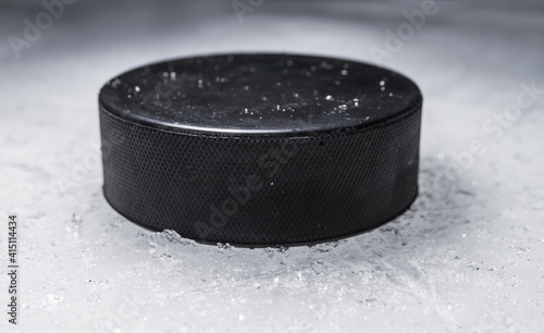Black hockey puck on the ice rink.