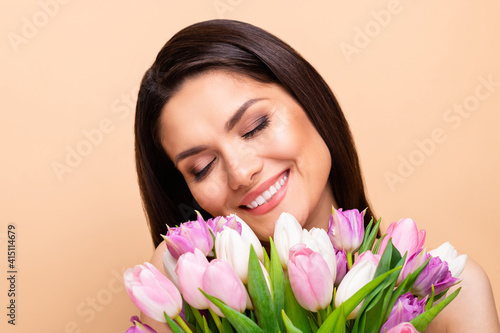 Photo of peaceful beautiful young woman hold flowers naked shoulders salon treatment isolated on beige color background