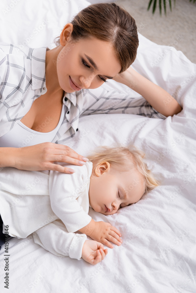 overhead view of happy mother touching sleeping son overhead view of happy mother touching sleeping son